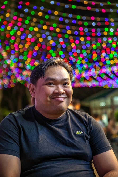 A man smiling in front of a colorful light display