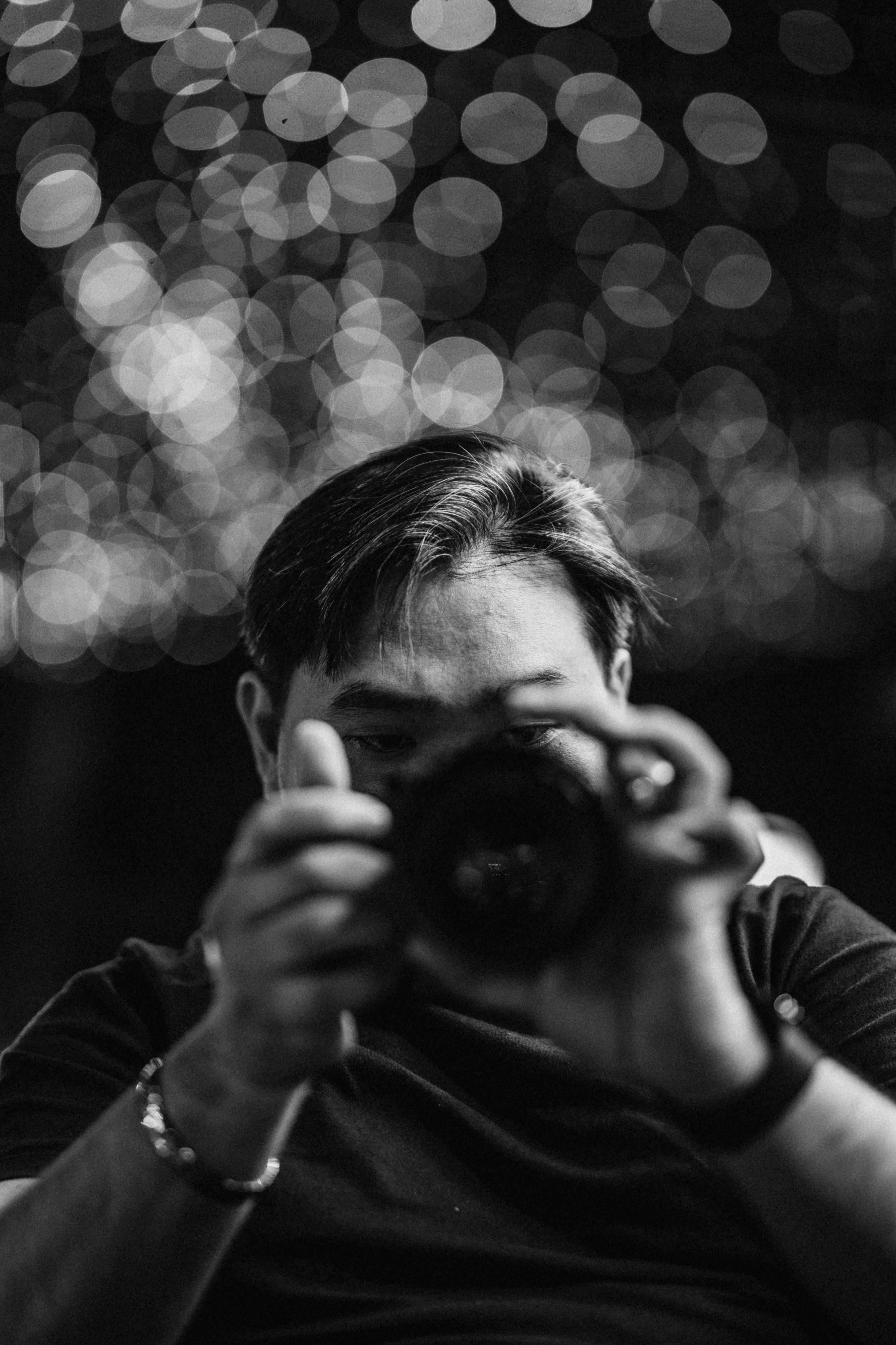 A creative black and white portrait of a man with a camera, capturing bokeh effects.