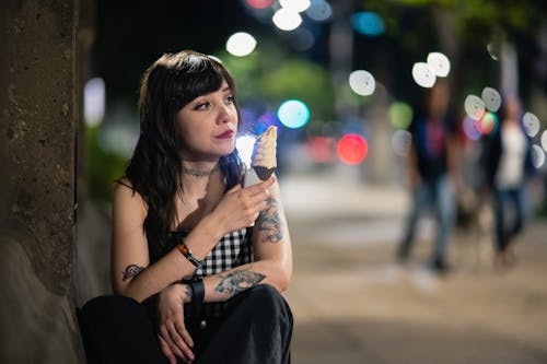 A woman sitting on a bench eating an ice cream cone