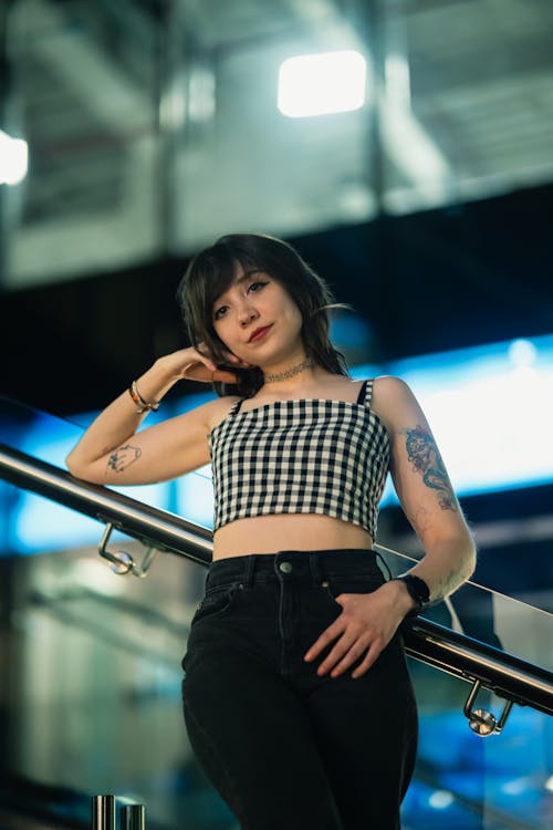 A woman in a crop top and jeans standing on a railing