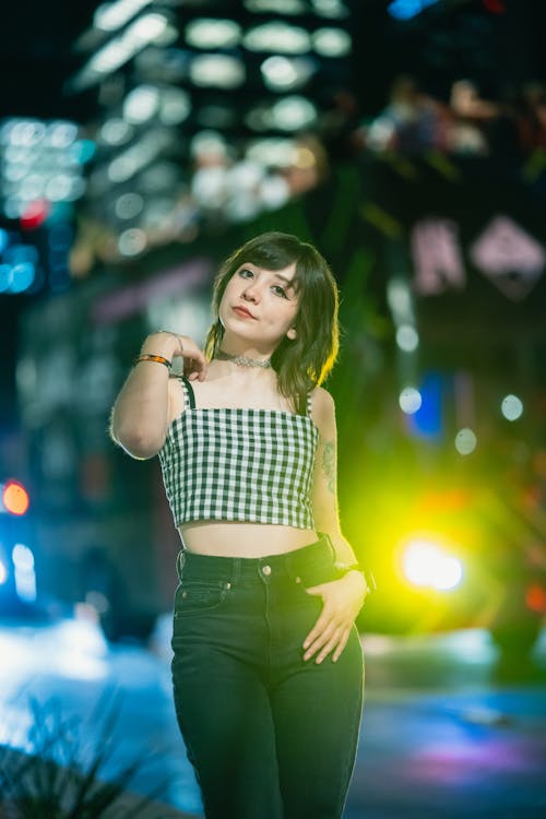 A woman in a crop top and jeans standing in front of a city street