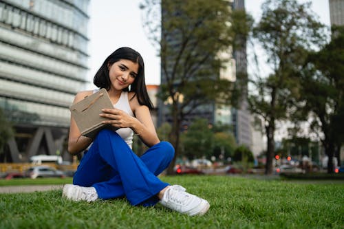Brunette Woman Sitting with Tablet in City