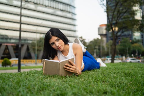 A woman laying on the grass reading a book