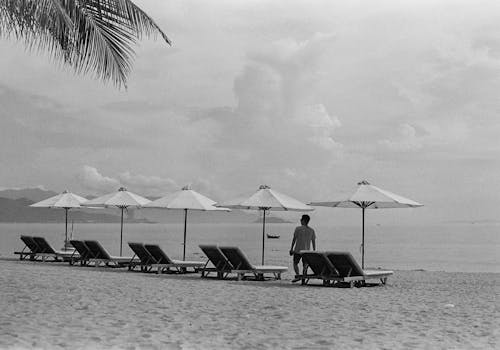 A black and white photo of a beach with chairs and umbrellas