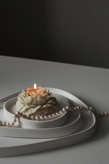 A close-up of a decorative candle shaped like a rose, adorned with pearls, providing a serene atmosphere.