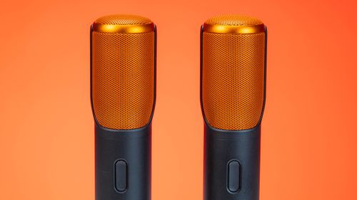 Free Vibrant photo of two modern microphones against an orange background, highlighting technology. Stock Photo