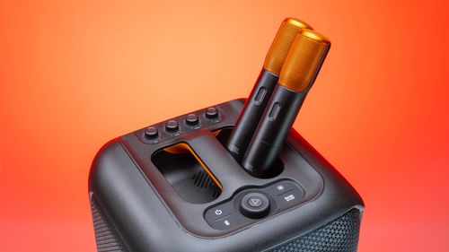 Free Close-up of modern microphone and speaker setup on a vibrant orange background. Stock Photo