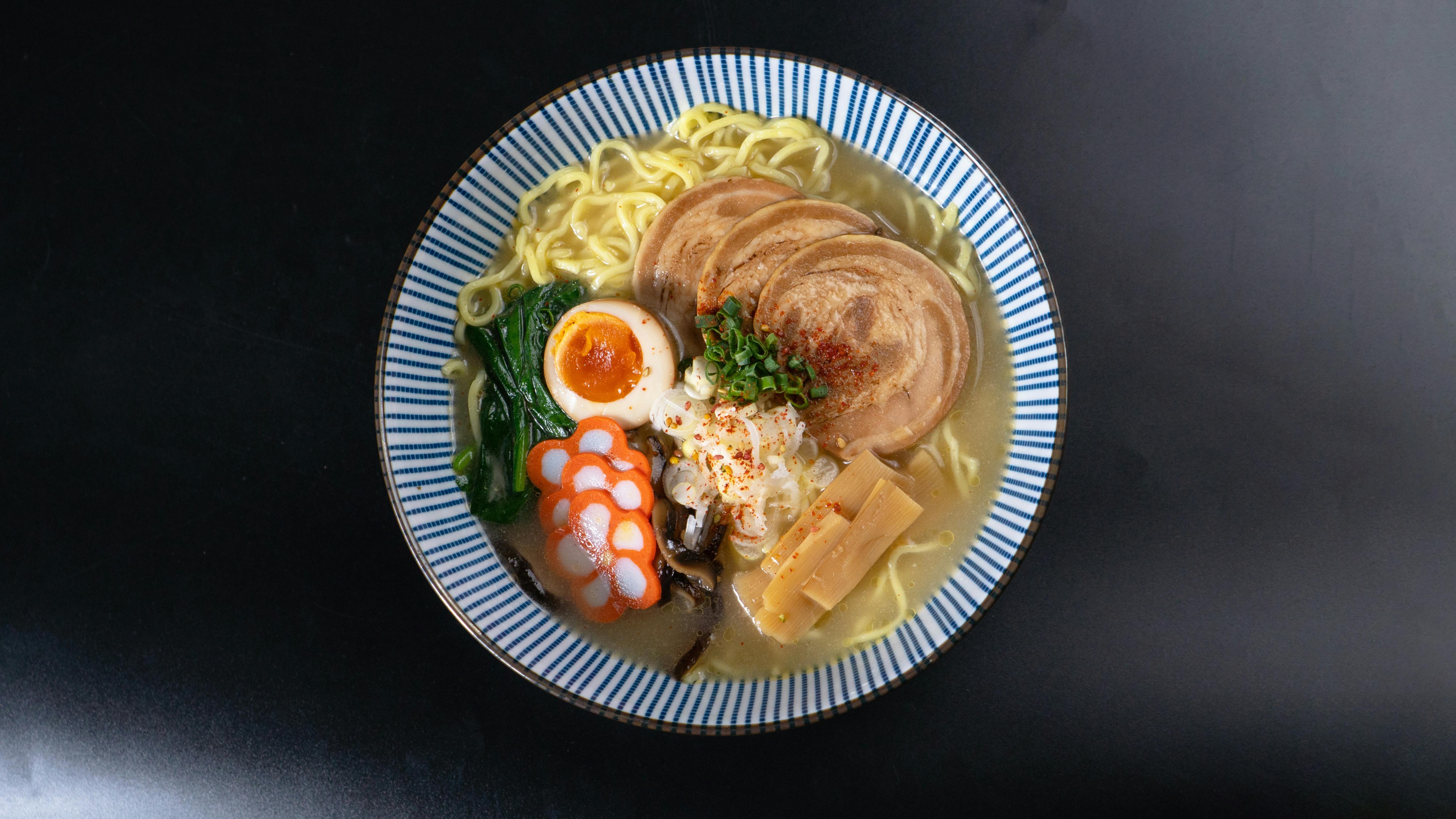 A flavorful bowl of ramen with various toppings served on a black background, perfect for food enthusiasts.