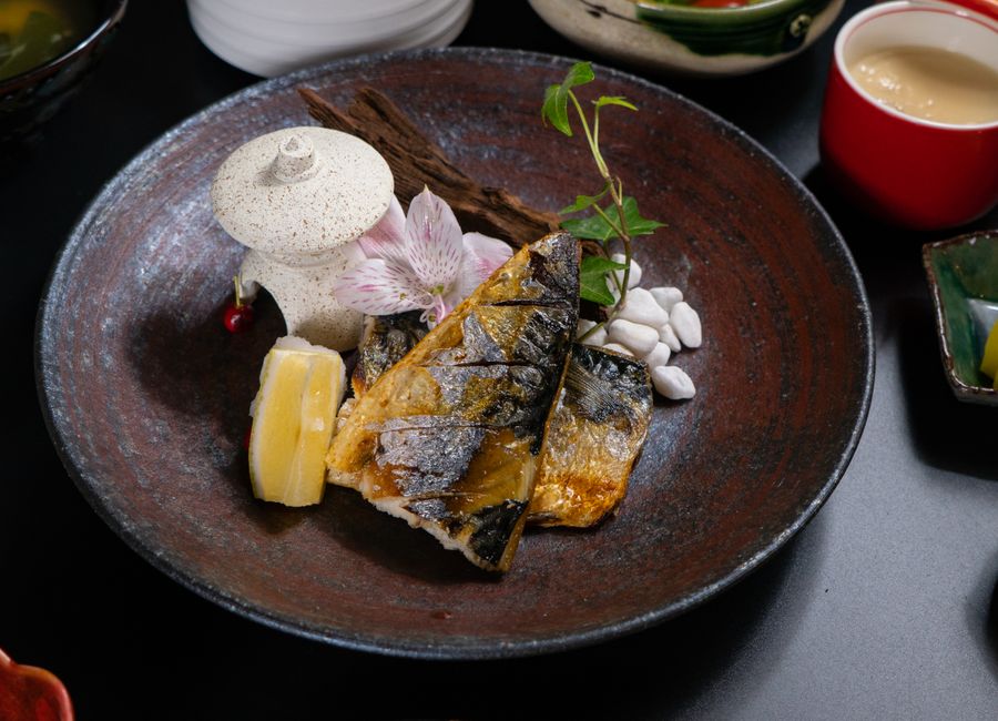 Close-up of a gourmet grilled fish dish with delicate presentation on a ceramic plate.