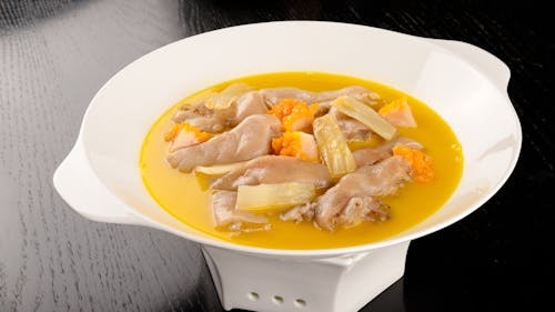A bowl of soup with chicken and vegetables