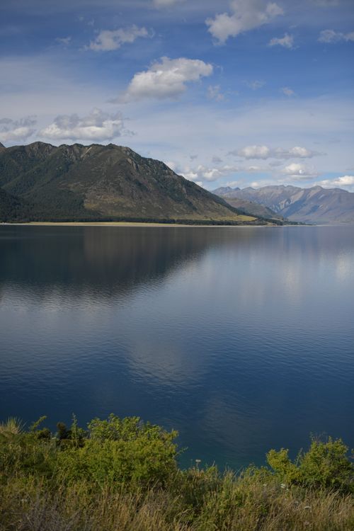 Free Tranquil view of The Neck, Otago with mountain reflections on the lake under a clear blue sky. Stock Photo