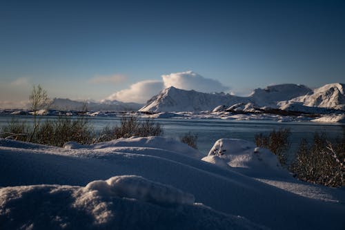 A snowy landscape with mountains and water