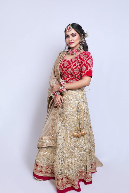 A beautiful woman in a red and gold lehenga