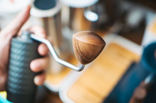 A person holding a wooden coffee grinder
