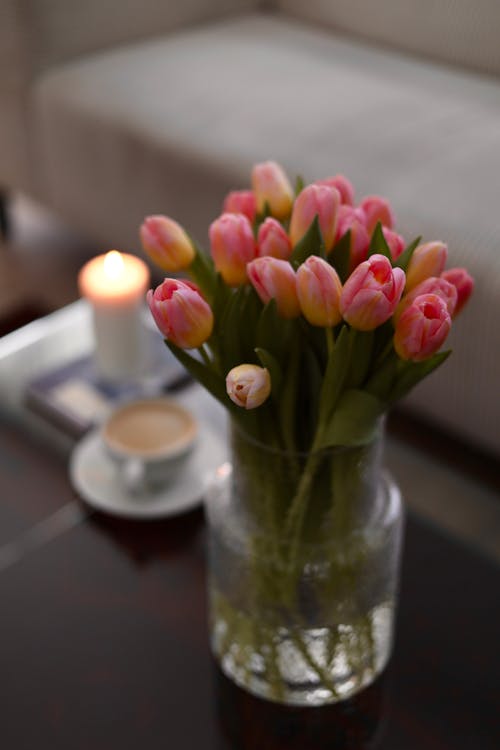 A vase of flowers on a table with a candle