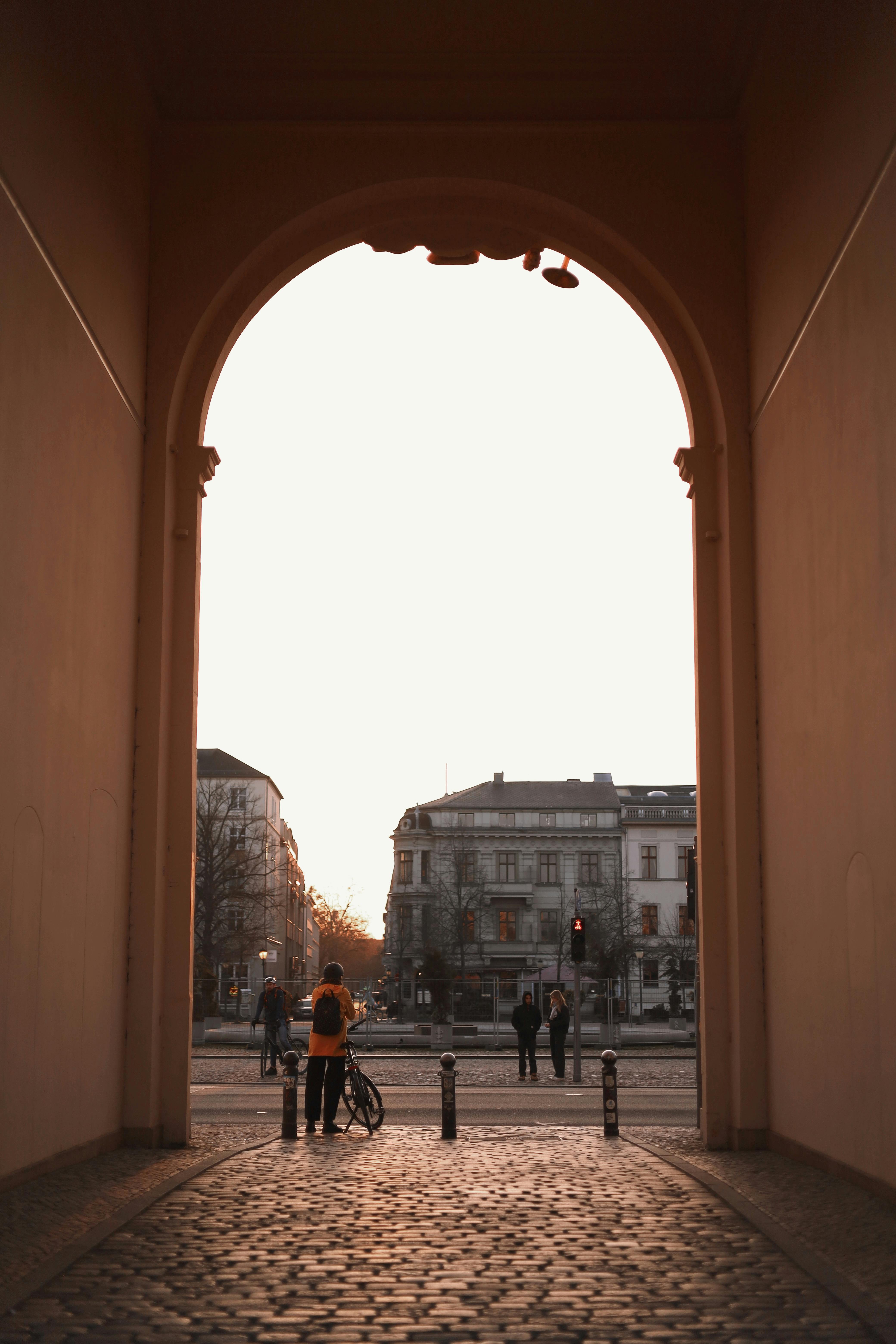 Warm sunset light frames an archway in Potsdam, capturing city streets and silhouettes.