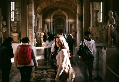Free Tourists exploring the historic corridors of the Vatican Museums, surrounded by ancient sculptures and art. Stock Photo