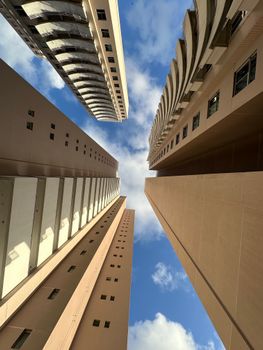 A striking upward view of skyscrapers against a patchy blue sky, emphasizing modern urban architecture.