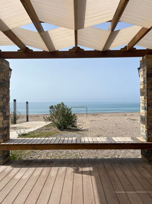 Free Serene view of a beach from a wooden terrace with clear blue sky. Stock Photo