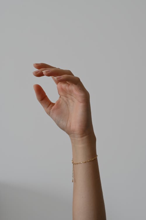 A hand is holding a bracelet on a white background