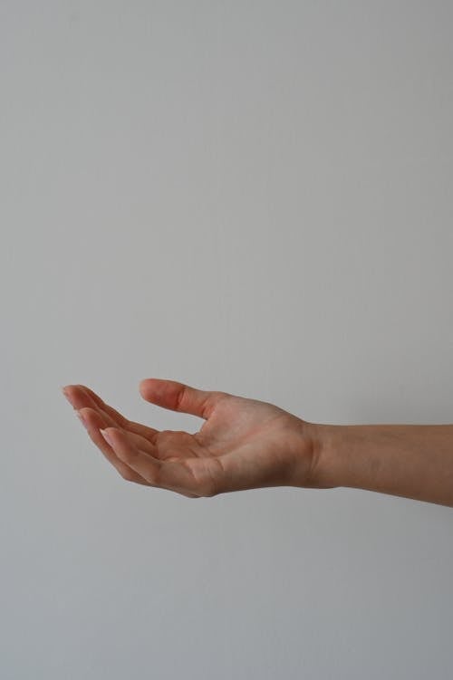 A person's hand is outstretched in front of a white wall