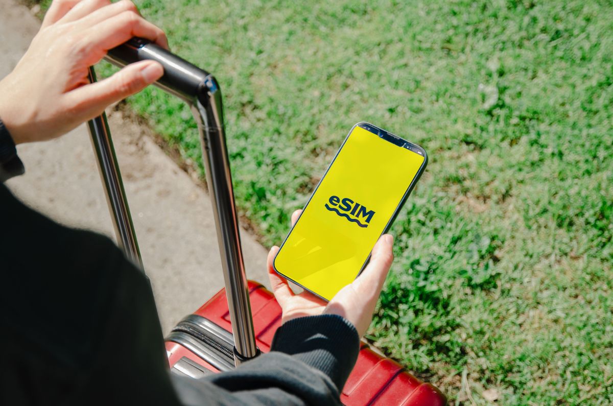 A traveler holding a smartphone showing an eSIM activation screen next to a passport