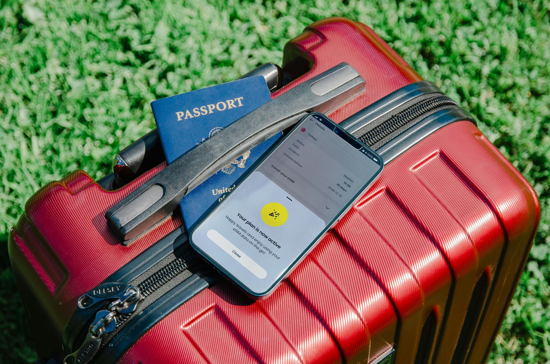 Close-up of a passport and smartphone on a red suitcase, perfect for travel themes.