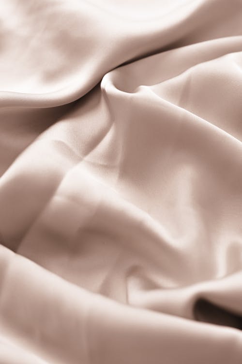 A close up of a silk sheet with a light pink color