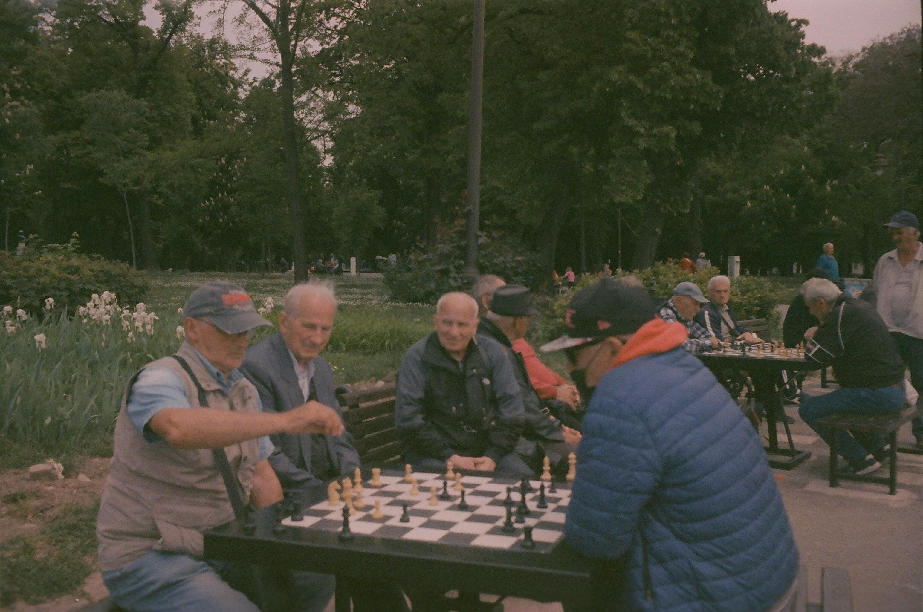 People playing chess in a park with benches