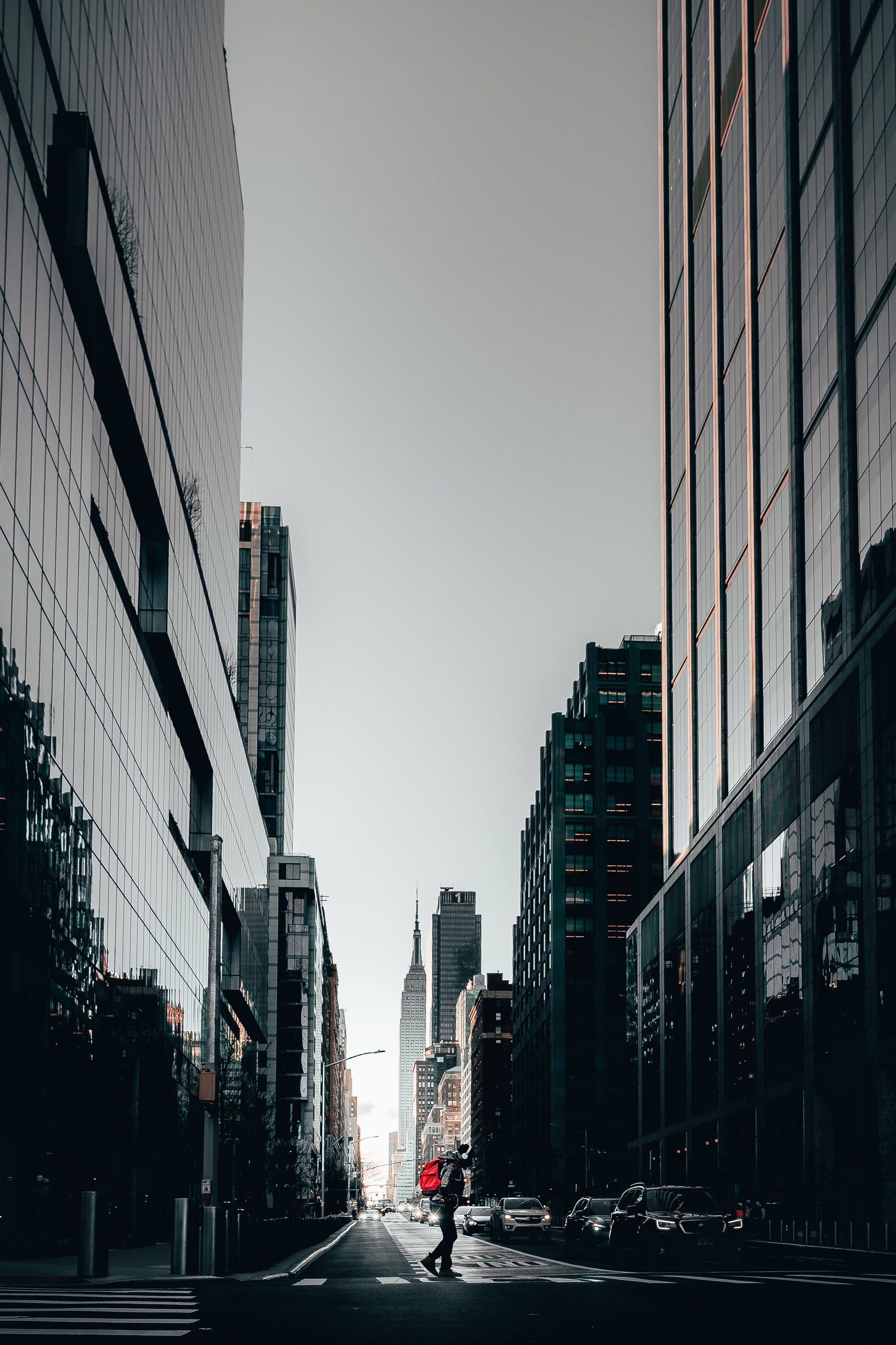 Silhouette of a person crossing a street in a downtown cityscape with skyscrapers.
