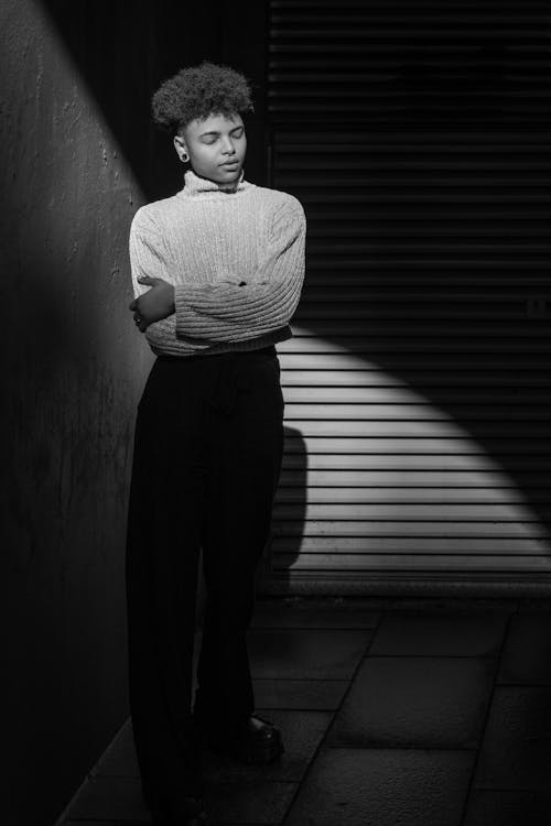 A black and white photo of a woman standing in front of a wall