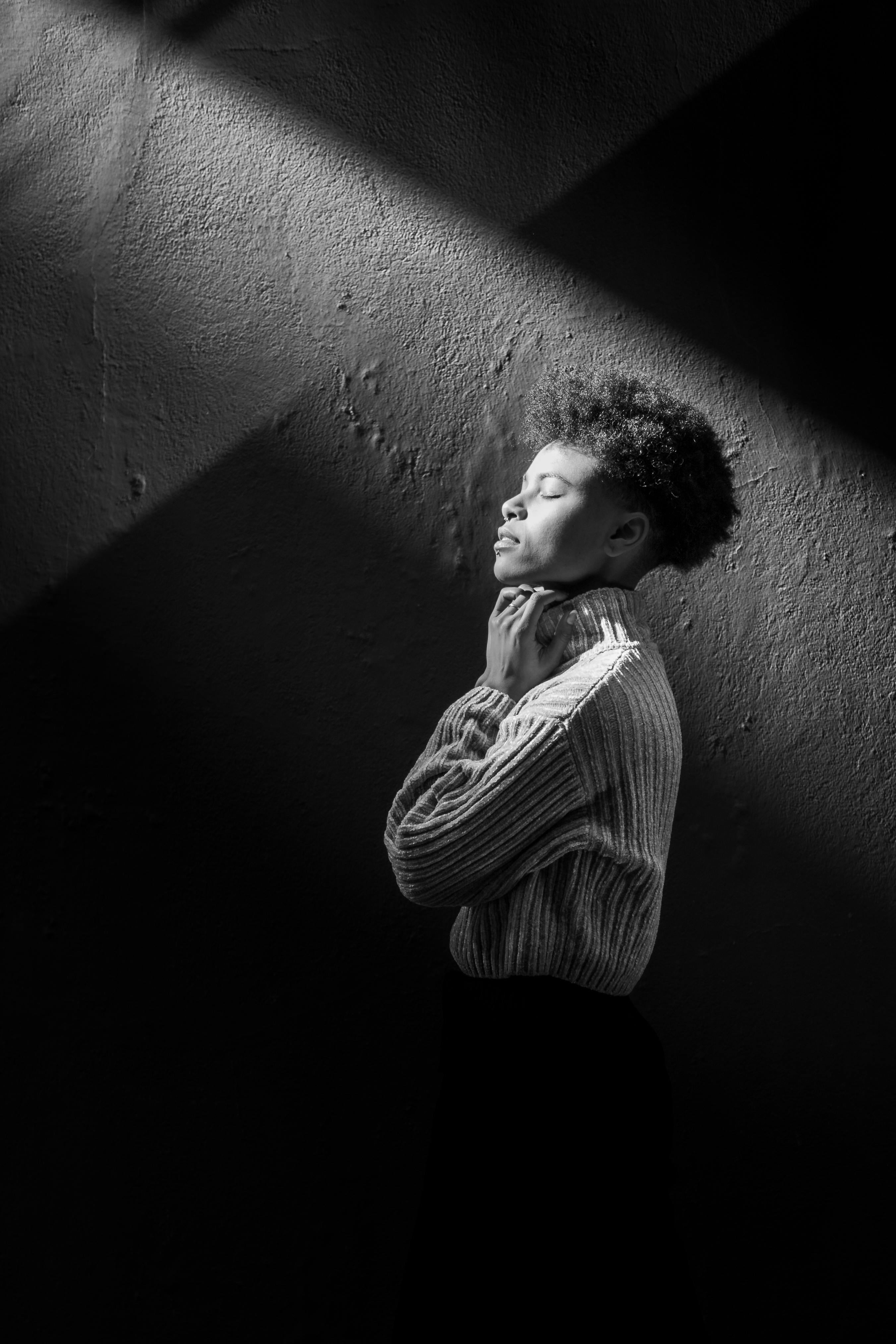 A striking black and white portrait of a woman in profile, bathed in dramatic light.