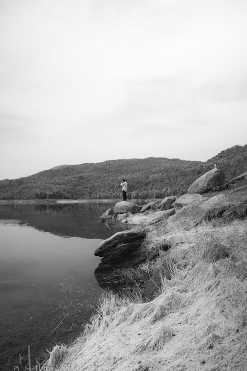 A black and white photo of a person standing on a rock