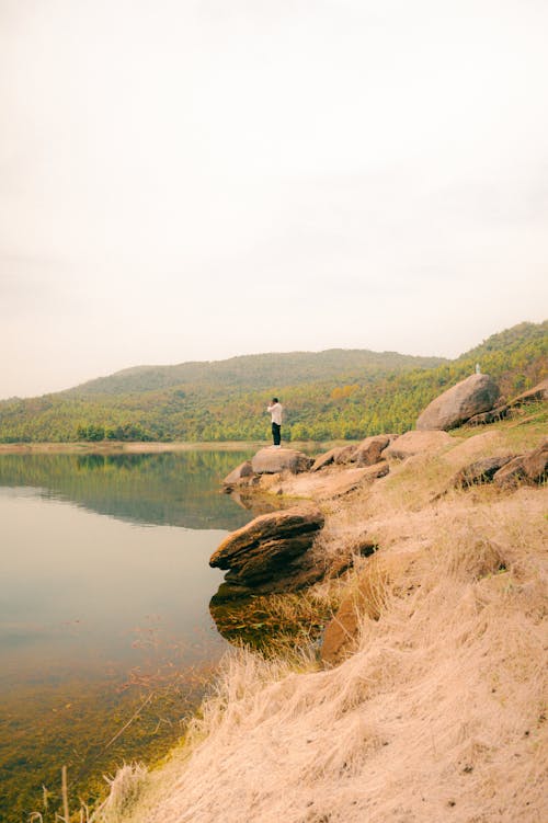 A person standing on the shore of a lake