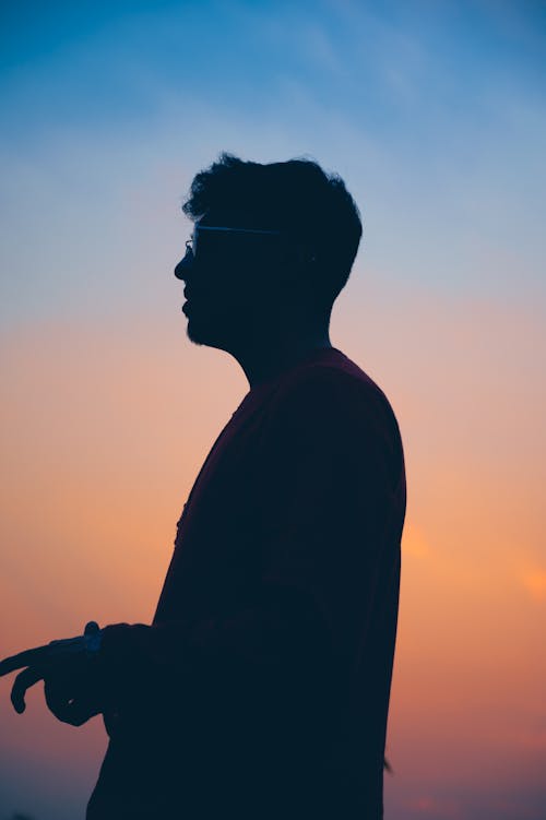 A silhouette of a man standing in front of a sunset