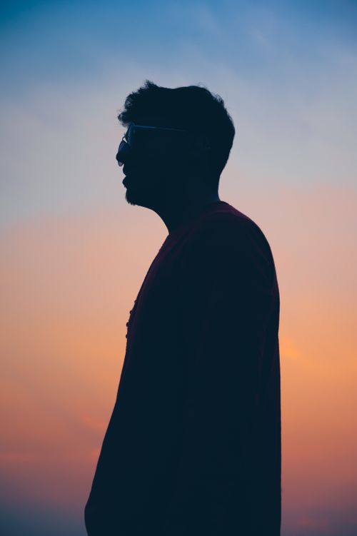 Free Profile silhouette of a man wearing eyeglasses against a colorful sunset sky, creating a striking visual contrast. Stock Photo