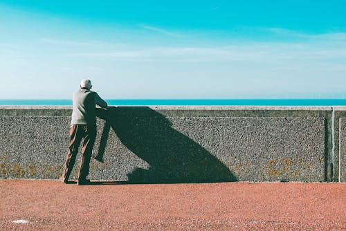 Homme Appuyé Sur Un Mur De Béton Gris Sous Le Ciel Bleu