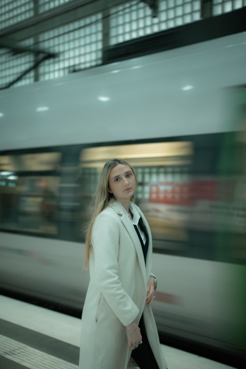 Free A fashionable woman poses at a bustling train station in Leipzig, showcasing city style. Stock Photo