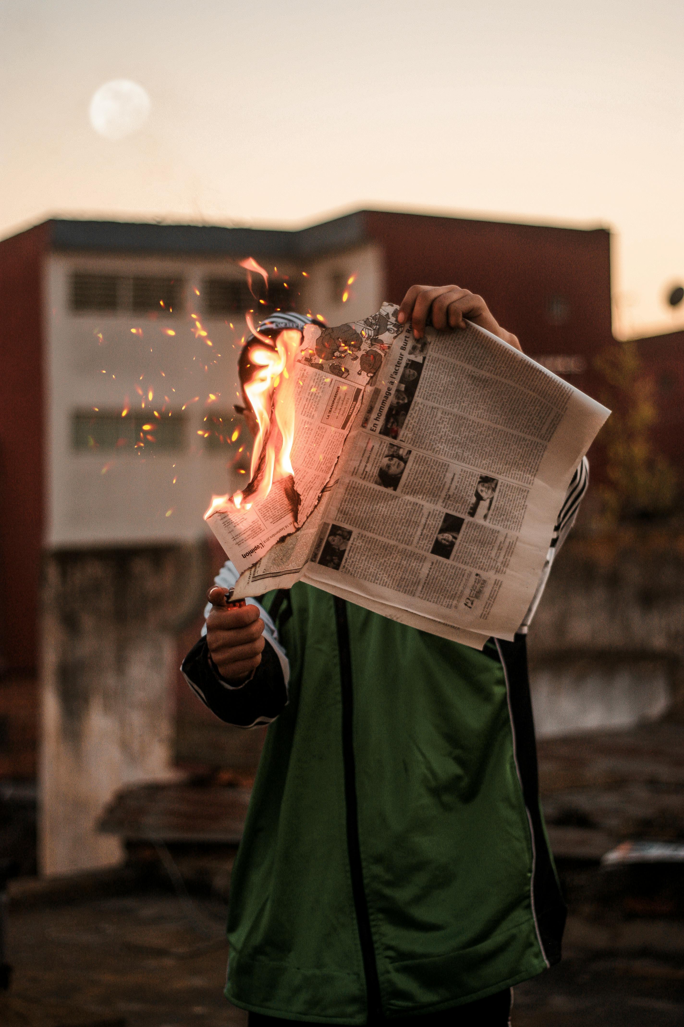 person in green jacket burning newspaper