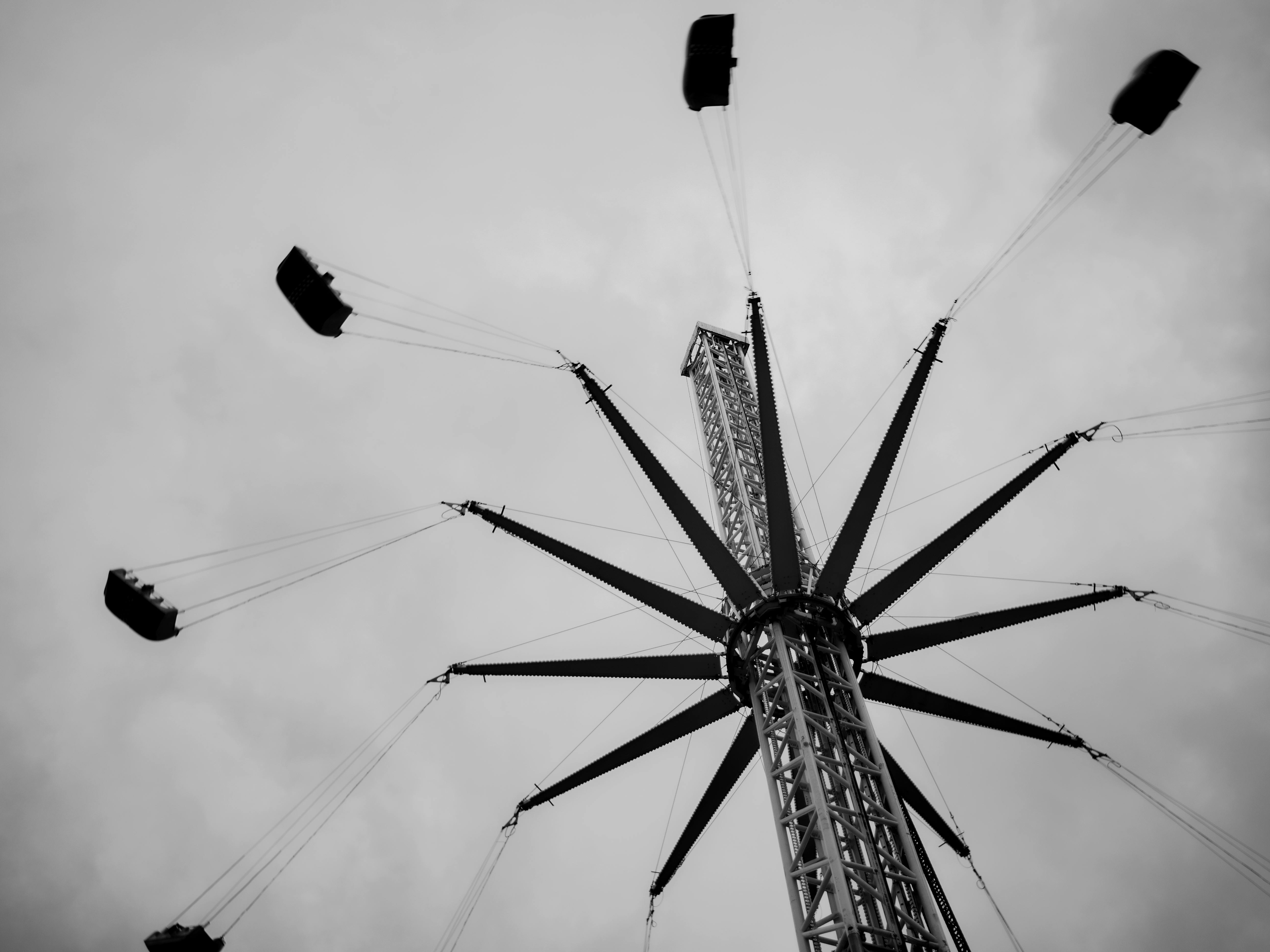 Black and white photo of a towering amusement park ride against a cloudy sky.