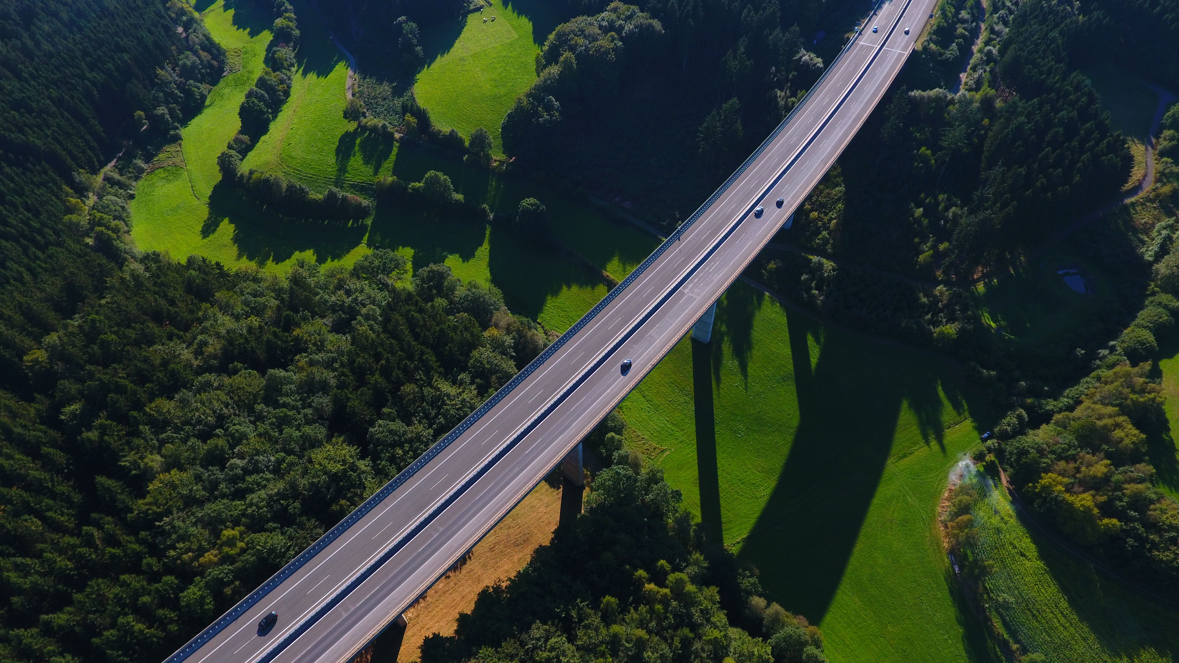Aerial view of a scenic elevated road through a lush green forest in Olpe, NRW, Germany.