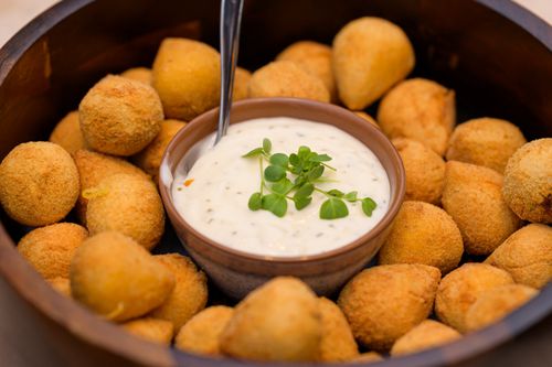 Free Crispy fried potato balls surrounding a bowl of creamy dip, garnished with herbs. Stock Photo