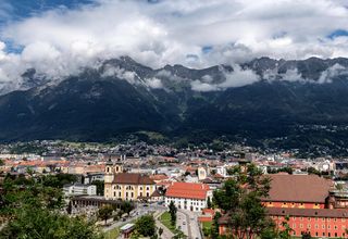 A breathtaking aerial view of Innsbruck, Austria, framed by majestic mountains and vibrant urban life.