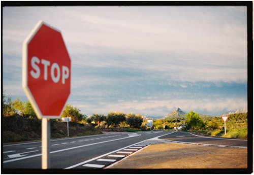 A stop sign on the side of the road with a road in the background