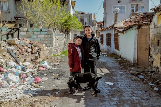 Smiling Boys Standing with Dog in Alley with Damaged Buildings in Town