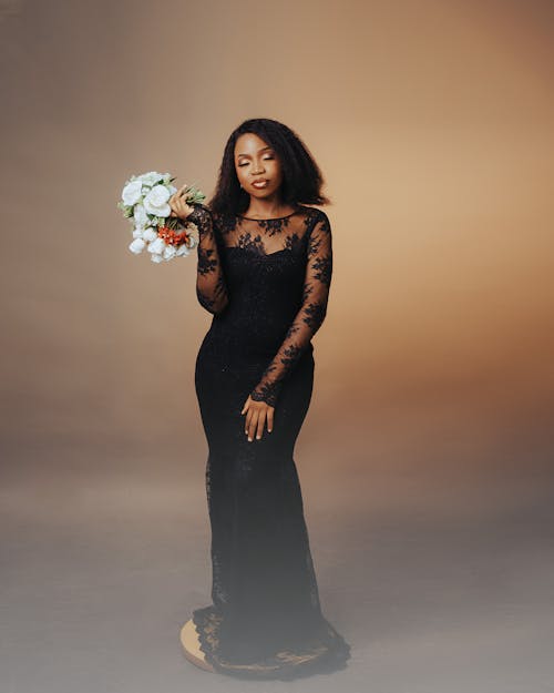 A woman in a black lace gown holding a bouquet