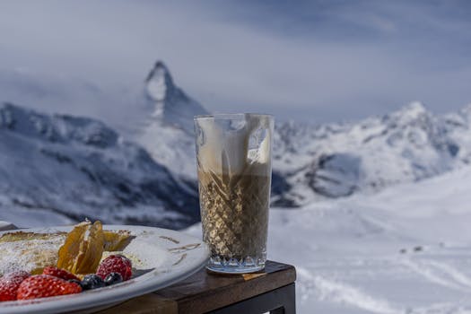A steaming beverage with dessert in front of the iconic Matterhorn in winter.