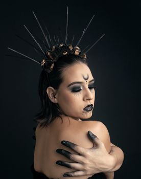 Elegant gothic portrait with intricate black makeup and floral wreath, embodying mysterious beauty.