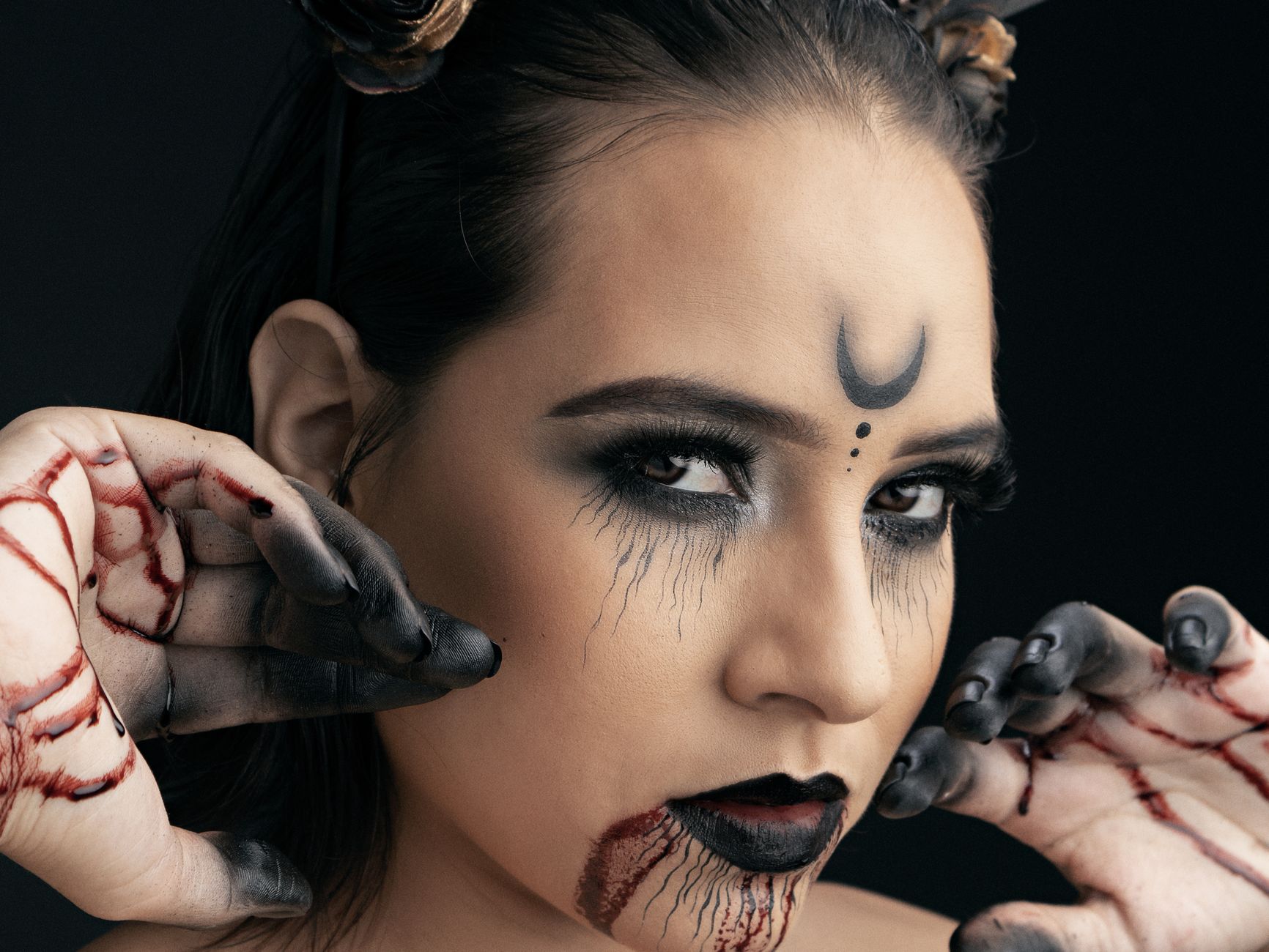 Close-up portrait of a woman in spooky Halloween makeup with dark tones and intricate face art.