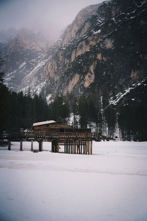 A wooden cabin in the snow near a mountain